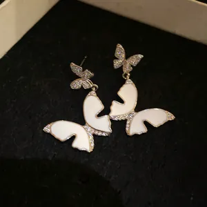 Close-up of elegant French style butterfly earrings with white enamel and zircons.