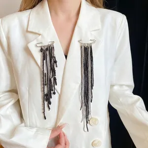 Elegant long tassel safety pin brooches with black beads on white blazer