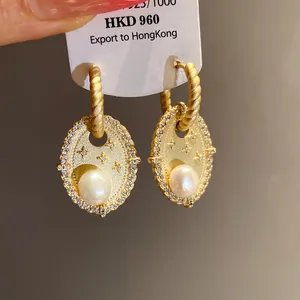 Detailansicht eleganter goldener Oval-Ohrringe mit Süßwasserperlen und Zirkonia-Steinen.