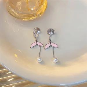 Dettaglio di eleganti orecchini a coda di pesce rosa con perle e zirconi brillanti