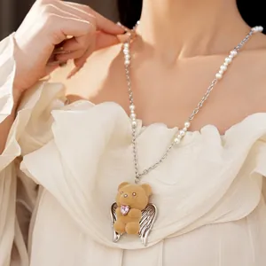 Primo piano elegante di una collana con orsetto floccato, ali d'angelo e dettagli di perle