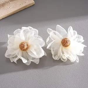 Detailed macro view showing handmade chiffon petals and woven raffia centers of flower earrings