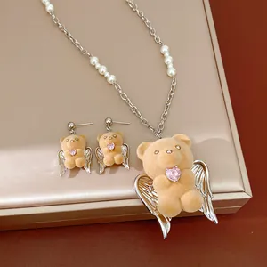 Dettaglio di un set di gioielli con orsetto angelo, perle e zirconi a cuore rosa
