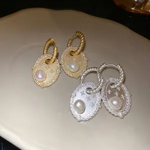 Detailansicht von ovalen Süßwasserperlen-Ohrringen mit Zirkonia in Gold und Silber