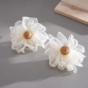 Detailed view of handmade white chiffon petal earrings featuring woven raffia centers