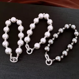 Drei elegante Perlenarmbänder mit funkelnden Zirkonia-Verschlüssen auf dunklem Display