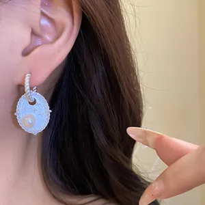 Nahaufnahme eleganter silberner Oval-Ohrringe mit Süßwasserperle und Zirkonsternen