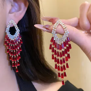 Primo piano di orecchini di strass eleganti con nappe di pietre preziose rosse rettangolari