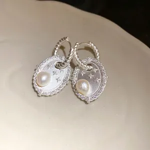 Exquisite Details eleganter silberner Ovalohrringe mit Süßwasserperle und Zirkoniasternen.