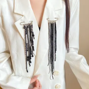 Detail view of vintage long tassel safety pin brooch with black beads on a white blazer