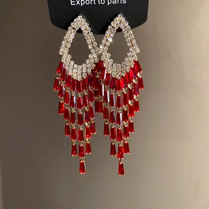Dettaglio di orecchini con lunghe nappe in cristallo rosso e strass scintillanti.