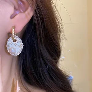 Detailansicht eleganter goldener Zirkon-Ohrringe mit Süßwasserperle