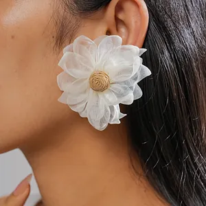 Detailed close-up of elegant white chiffon flower earrings with raffia grass center woven detail