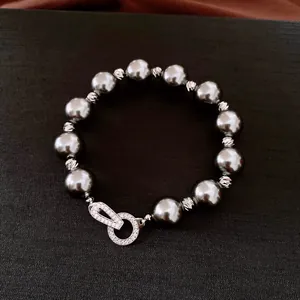 Detailansicht eines grauen Perlenarmbands mit funkelndem Zirkon-Verschluss im Vintage-Stil.