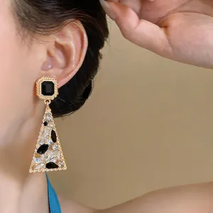 Primo piano di orecchini vintage dorati geometrici con pietre nere e trasparenti lucide