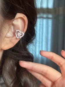 Close-up of heart-shaped silver ear cuff with sparkling cubic zirconia on ear
