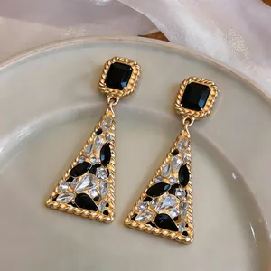 Vista dettagliata di orecchini vintage in oro con strass neri e trasparenti geometrici