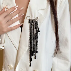 Detailed view of a vintage-style long tassel safety pin brooch with black beads and silver chains