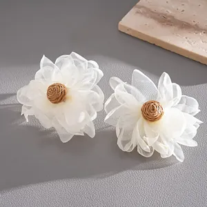 Detail view of handmade white chiffon flower stud earrings with raffia centers