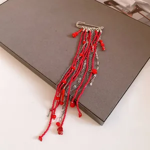 Close-up detail of red bead and silver chain tassels on a vintage paperclip brooch.