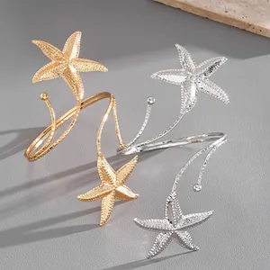 Detailed macro view of textured starfish open arm cuffs in gold and silver finishes