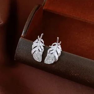 Exquisite close-up detail of silver feather stud earrings with sparkling micro diamonds