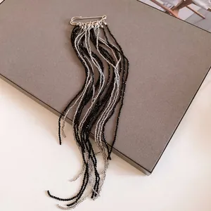 Detail of long tassel safety pin brooch with black and silver beaded strands.