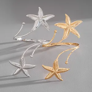 Macro detail of elegant gold and silver starfish open arm cuffs with a textured metal finish