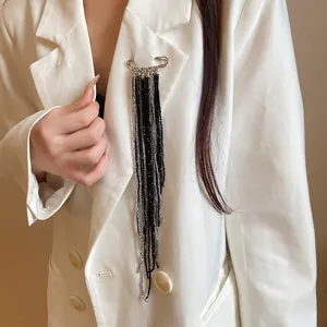 Detailed view of a retro safety pin brooch with long black and silver beaded tassels