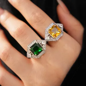 Close-up of vintage square rings with green and yellow gemstones in a detailed palace style.