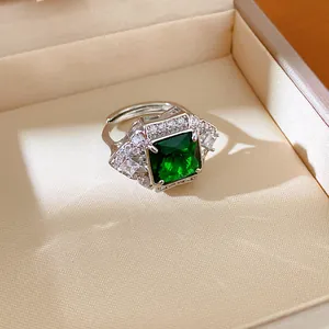 Close-up of elegant silver-toned ring with a large square emerald green gemstone.