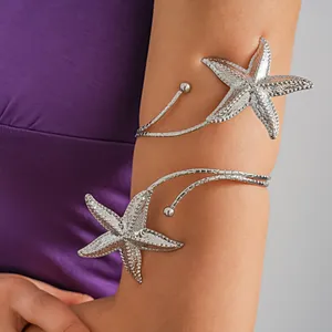 Close-up of silver starfish arm cuff worn on upper arm for coastal vacation style.