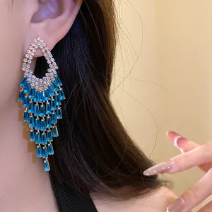 Dettaglio di orecchini di lusso con nappe blu e cristalli su modella