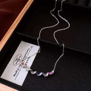 Detail view of a silver smile necklace with colorful oval stones and twisted metal.