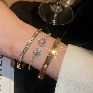 Set of three luxury gold-finish bangles with heart charms and cubic zirconia accents for women