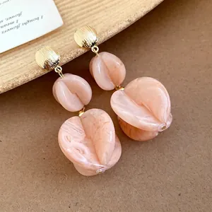 Elegant peach acrylic tiered drop earrings with golden studs for a vacation style look.