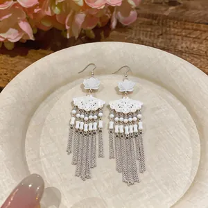 Close-up of elegant Chinese style fan-shaped earrings with long silver tassels
