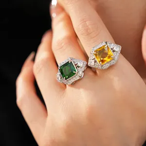 Close-up of vintage palace style geometric rings with green and yellow gemstones on hand