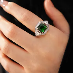 Close-up of vintage palace style silver ring with square green zircon on finger