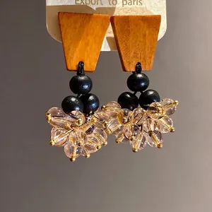 Boucles d'oreilles ethniques en bois avec perles noires et perles roses.