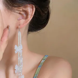 Dettaglio ravvicinato di un orecchino lungo a nappa con farfalle in chiffon e perle.