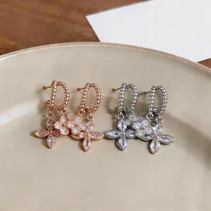 Macro detail of elegant flower zircon dangle earrings in silver and rose gold finishes.
