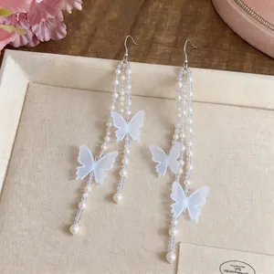 Primo piano di orecchini a farfalla in chiffon bianco con perle e nappe lunghe