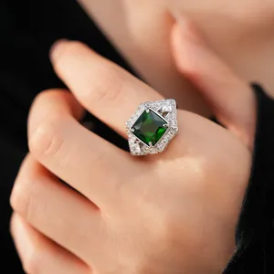 Close-up of a silver-toned ring with a large square green zircon and crystal accents