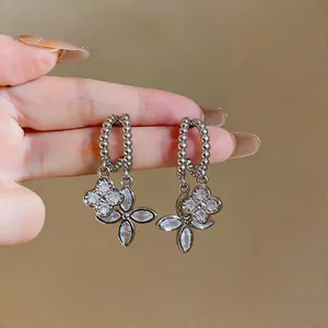 Detailed close-up showing silver beaded hoop earrings with sparkling zircon flower pendants