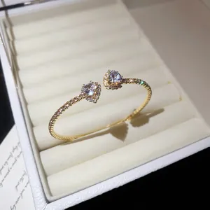 Close-up of elegant gold open-cuff bracelet with two heart-shaped gemstones