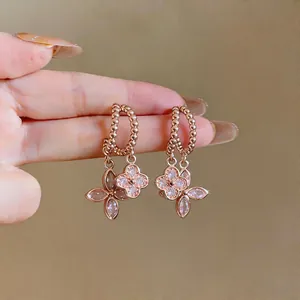 Close-up of rose gold flower earrings with sparkling zircon stones and beaded hoops