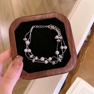 Primer plano detallado de una elegante pulsera de perlas multicapa en caja de madera