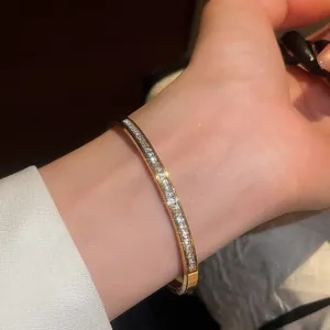 Elegant gold-toned bangle with shimmering zircon stones worn on a wrist in close-up view