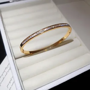 Close-up of elegant gold-toned bangle set with sparkling zircons in a white box.